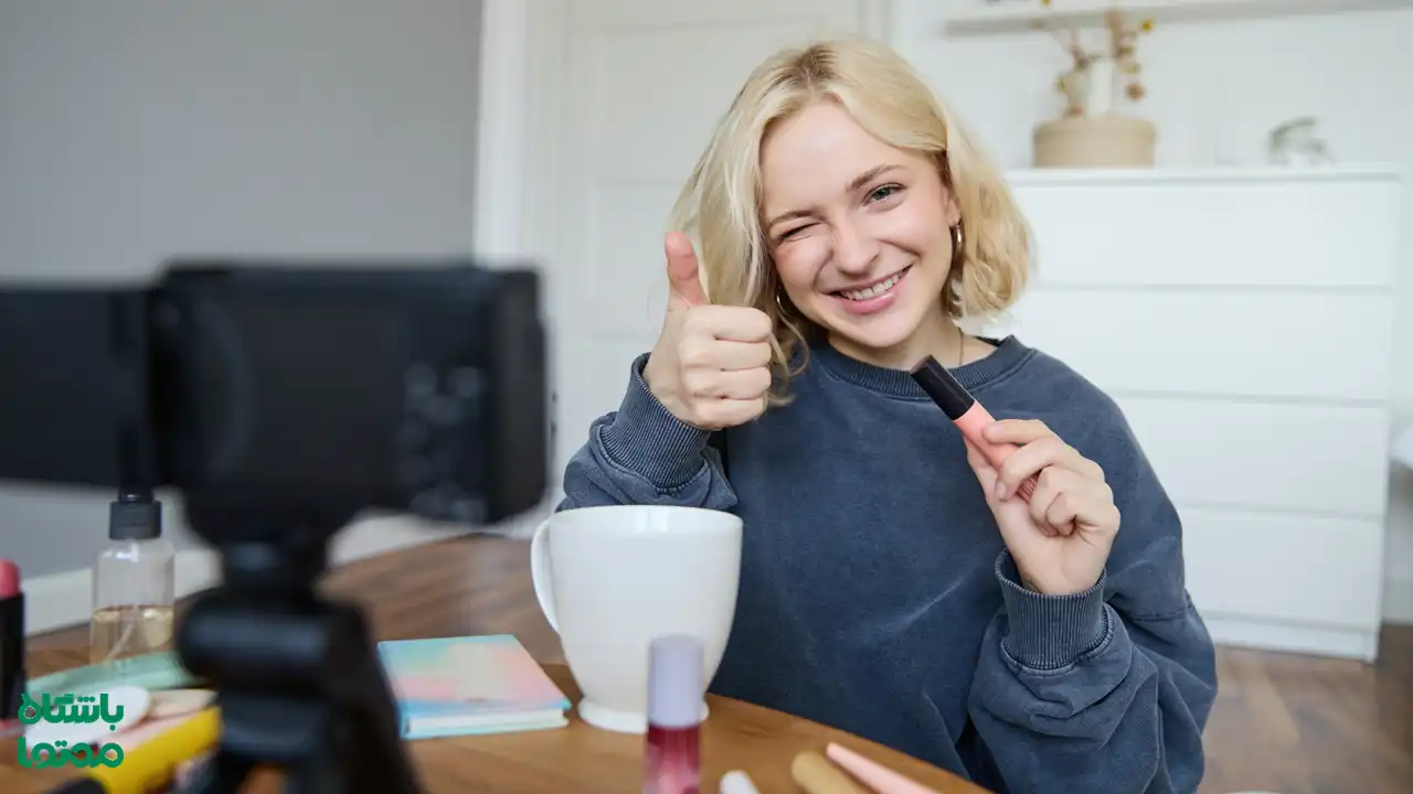 دختری خندان در حال ضبط ویدیو و معرفی محصول آرایشی در مقابل دوربین